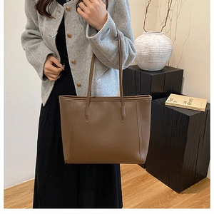 Detailed view of reinforced stitching on brown leather tote bag handle for daily commute