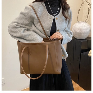 Brown leather large capacity tote bag shown on a model for shoulder wear