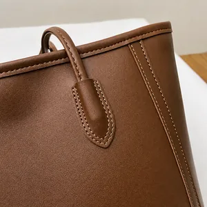 Close-up of neat stitching and leather texture on a brown large capacity tote bag