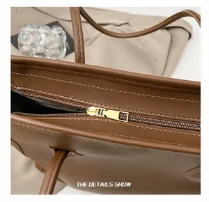 Detailed macro view of high-quality golden metal zipper on a dark brown leather tote bag