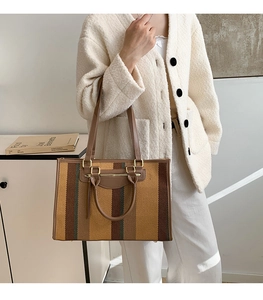 Detail of colorful striped canvas tote bag with brown faux leather handles and gold buckles