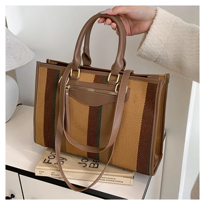 Detail of canvas tote bag showing striped texture and brown leather straps on a side table