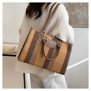 Close-up of canvas tote bag featuring vintage stripes and premium leather handle detail