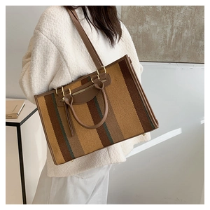 Detail of canvas tote bag showing striped pattern and brown leather straps