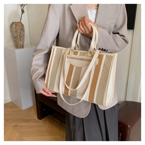 Close-up of the striped canvas tote bag showing weave texture and shoulder strap details
