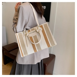 Lifestyle shot of large canvas tote with striped pattern and leather handles on model