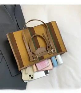 Flat lay of a large striped canvas tote bag showing interior storage for tablets and cosmetics