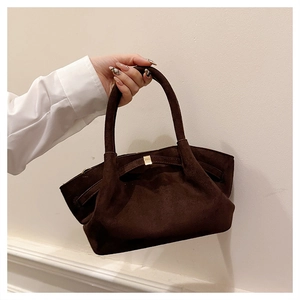 Détail d'un sac cabas en cuir mat marron foncé avec poignée unique et boucle en métal doré