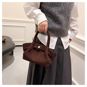 Détail du sac cabas en daim marron foncé avec un fermoir décoratif en métal doré rectangulaire