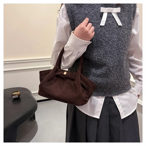 Détail du sac fourre-tout en daim marron avec plis et boucle métallique élégante