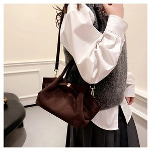 Détails de la texture en daim marron foncé mat et des boucles en métal doré sur le sac