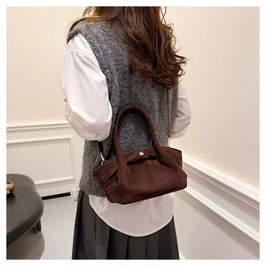 Détail du sac fourre-tout vintage en daim marron avec boucle dorée et bandoulière sur modèle