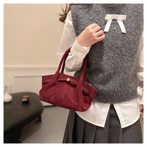 Sac fourre-tout bordeaux en daim avec nœud, porté par un mannequin en intérieur
