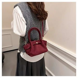 Détail macro du sac cabas en daim bordeaux avec ferrures dorées et bandoulière élégante