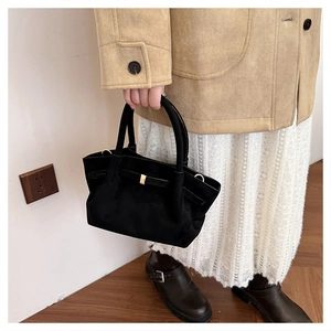 Détail d'un sac cabas noir mat avec un nœud papillon et une boucle carrée dorée