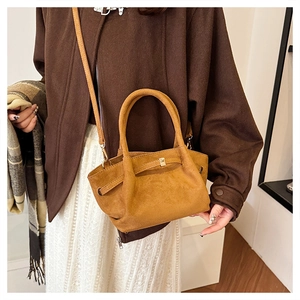 Détail du sac cabas en daim marron avec extensions latérales et boucle métallique