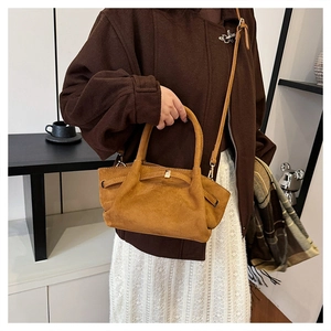 Sac cabas en daim marron avec anses cylindriques et détails dorés dans un décor moderne