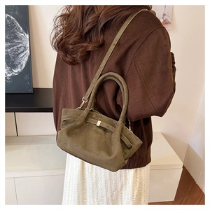 Gros plan sur le sac cabas en daim vert olive avec boucle dorée et bandoulière
