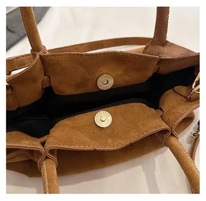 Détail du fermoir magnétique doré d'un sac cabas en daim marron avec doublure noire