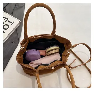 Vue de dessus du grand sac cabas en daim marron rempli d'objets du quotidien