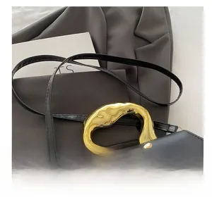 Close-up of black crossbody bag featuring a golden wave handle and 3D bow buckle
