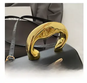 Detail of a black leather handbag with a sculptured gold handle and bow hardware