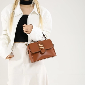 Brown PU leather crossbody handbag with oval gold metal buckle worn by model