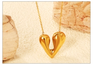 Détail macro d'un collier pendentif cœur doré poli sur un support en pierre naturelle