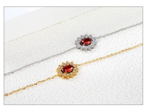 Close-up of gold and silver sunflower bracelets with red zircon stones on a white background