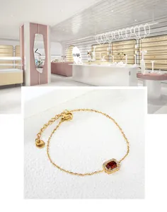 Détail du bracelet en acier doré avec zircon rouge carré et fermoir à mousqueton sécurisé