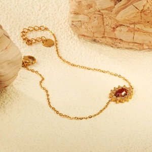 Elegant gold bracelet with oval red zircon sunflower pendant and lobster clasp on rock