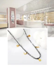 Détail du collier de perles avec pendentifs étoile, lune et éclair dorés sur perles grises