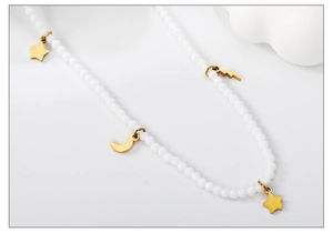 Détail macro du collier de perles avec breloques dorées d'étoile et de lune