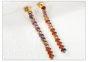 Dettaglio di eleganti orecchini pendenti dorati con cristalli ovali multicolore