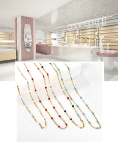 Detail of colorful beads on a gold stainless steel chain over white textured fabric