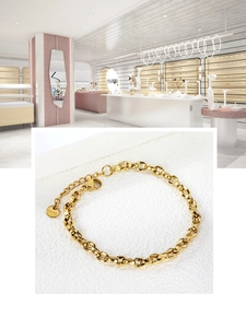 Detail of gold coffee bean link chain bracelet with lobster clasp and adjustable steel tag