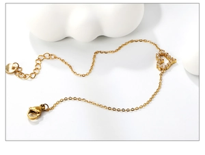 Detailed macro of gold heart charm bracelet featuring pavé zircon and lobster clasp