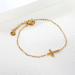 Detailed macro of a gold stainless steel zircon cross bracelet with adjustable lobster clasp