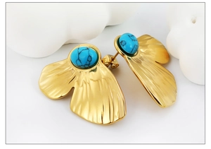 Detail of vintage 18K gold earrings with round turquoise stone and textured metal petals