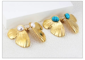 Close-up of golden fan earrings featuring white pearls and turquoise stones