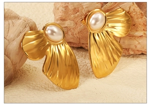 Macro detail of vintage gold fan-shaped earrings with white pearl inlay and metal texture