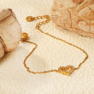 Elegant gold stainless steel heart bracelet with zircon stones on a summer sand background