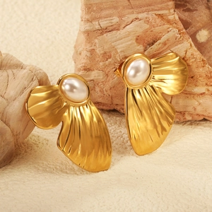 Vintage golden shell earrings with white pearls on a textured stone display