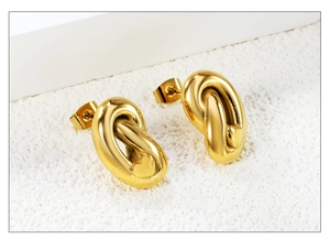 Detailed view of gold-plated twisted knot earrings with small heart-shaped accents