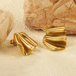 Irregular folded gold earrings with metallic texture on decorative stone base