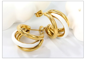 Macro detail of 18K gold-plated C-shape earrings with white enamel triple-hoop design