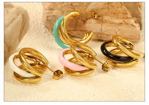 Detailed macro view of triple C-shape gold earrings with colorful enamel accents