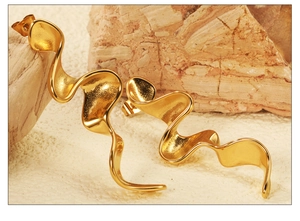 Detailed view of textured gold irregular wavy earrings on a rustic stone background
