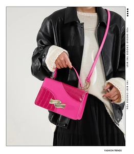 Detail of rose pink square handbag with crocodile embossing and golden wavy buckle