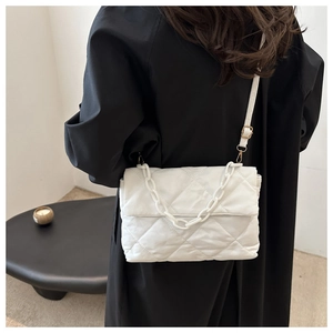 Close-up of white quilted puffer bag with plastic chain detail against black coat